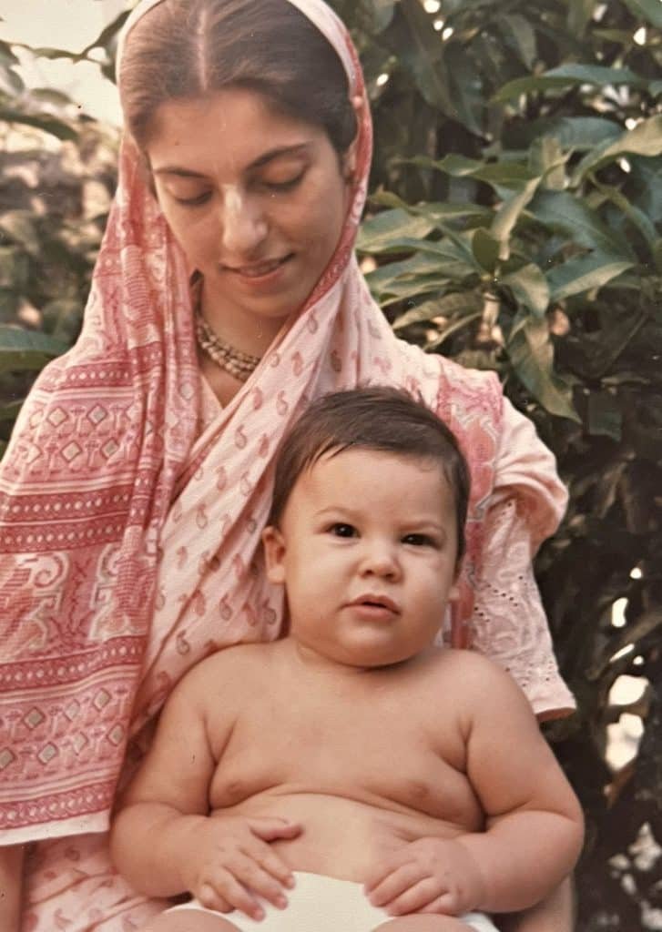 Smiling woman Angela Masuzzo in a pink saree holding a baby outdoors