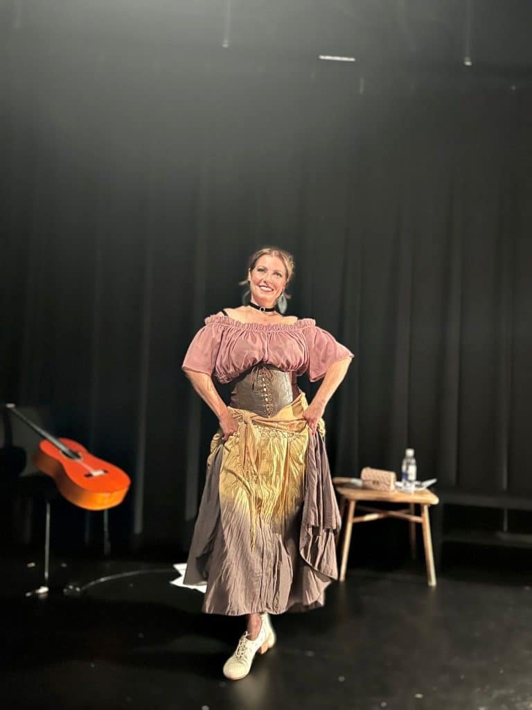 Smiling woman Angela Masuzzo in stage costume with guitar background