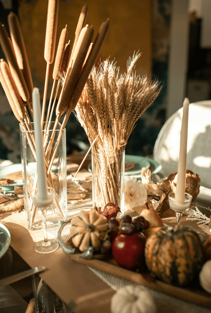 Autumn-themed table with candles, wheat, and gourds