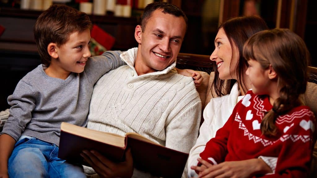 Happy family reading book together on cozy couch