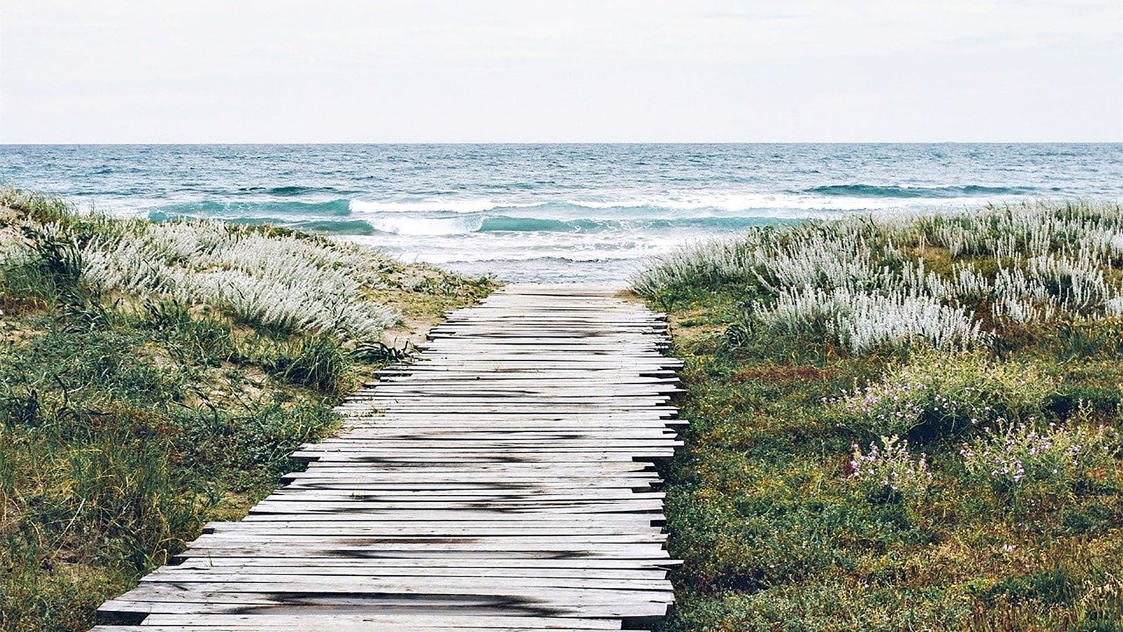Wooden path leading to a serene beach with gentle waves